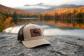 Beige and brown cap with a leather patch featuring a moose design 